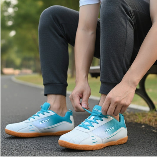 Person tying blue and white sneakers with orange soles on a blurred outdoor background